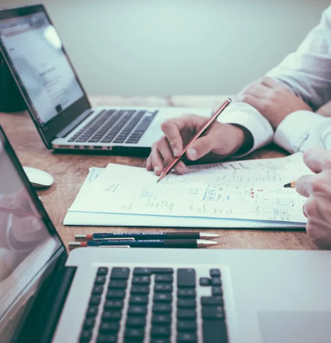 Sketches and notes beside two laptops while designing a website
