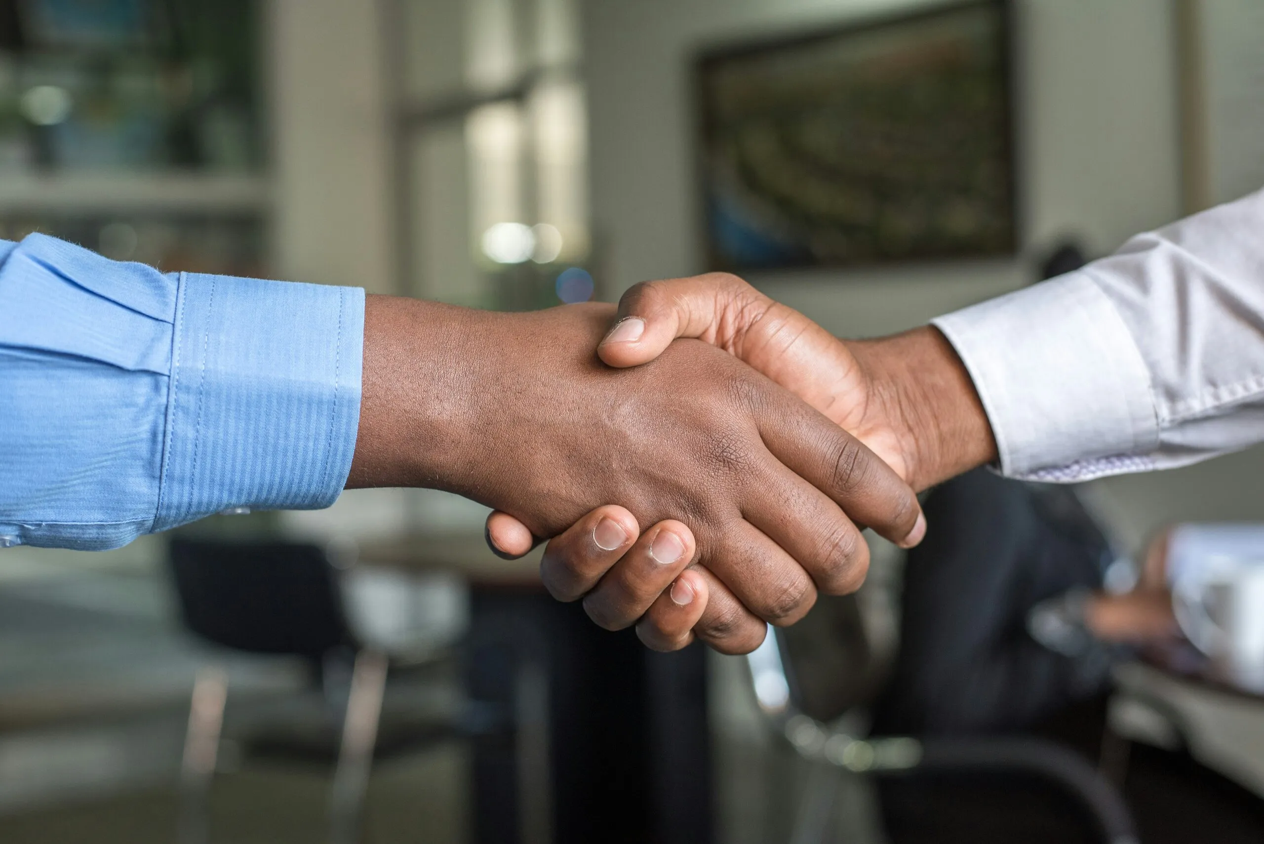 Twee professionals schudden elkaar de hand na het afronden van een digitaal contractproces.