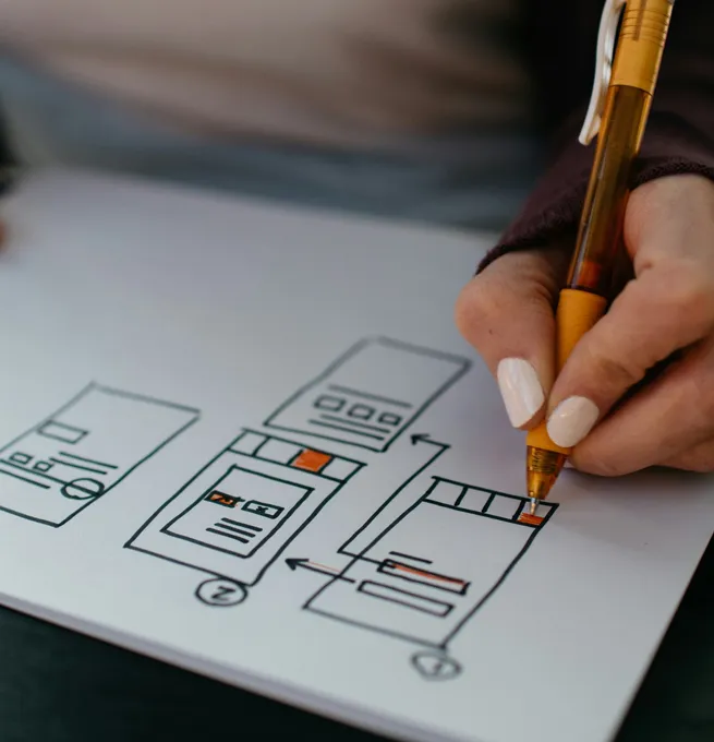 A hand sketching the layout of web pages on paper